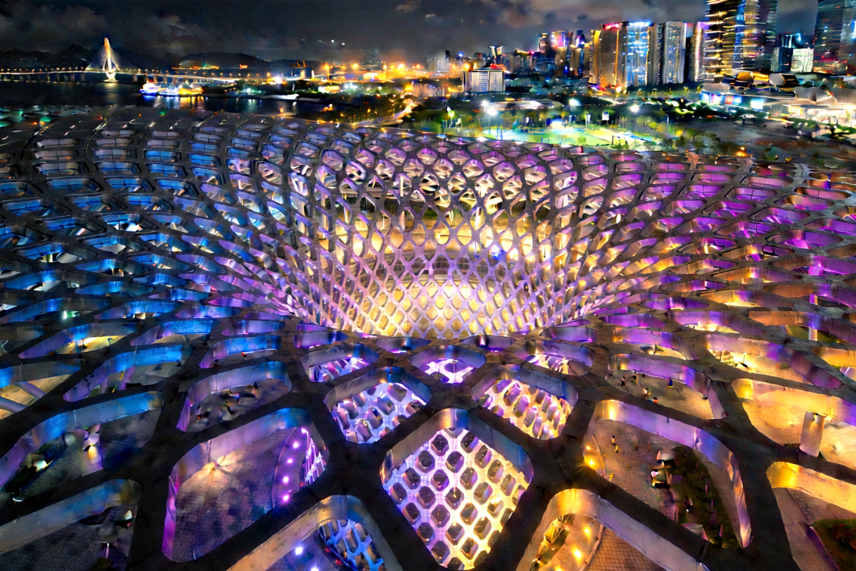 深圳湾体育中心‘春茧’外部景观，其独特的网格状钢结构在夜晚灯光下显得格外璀璨